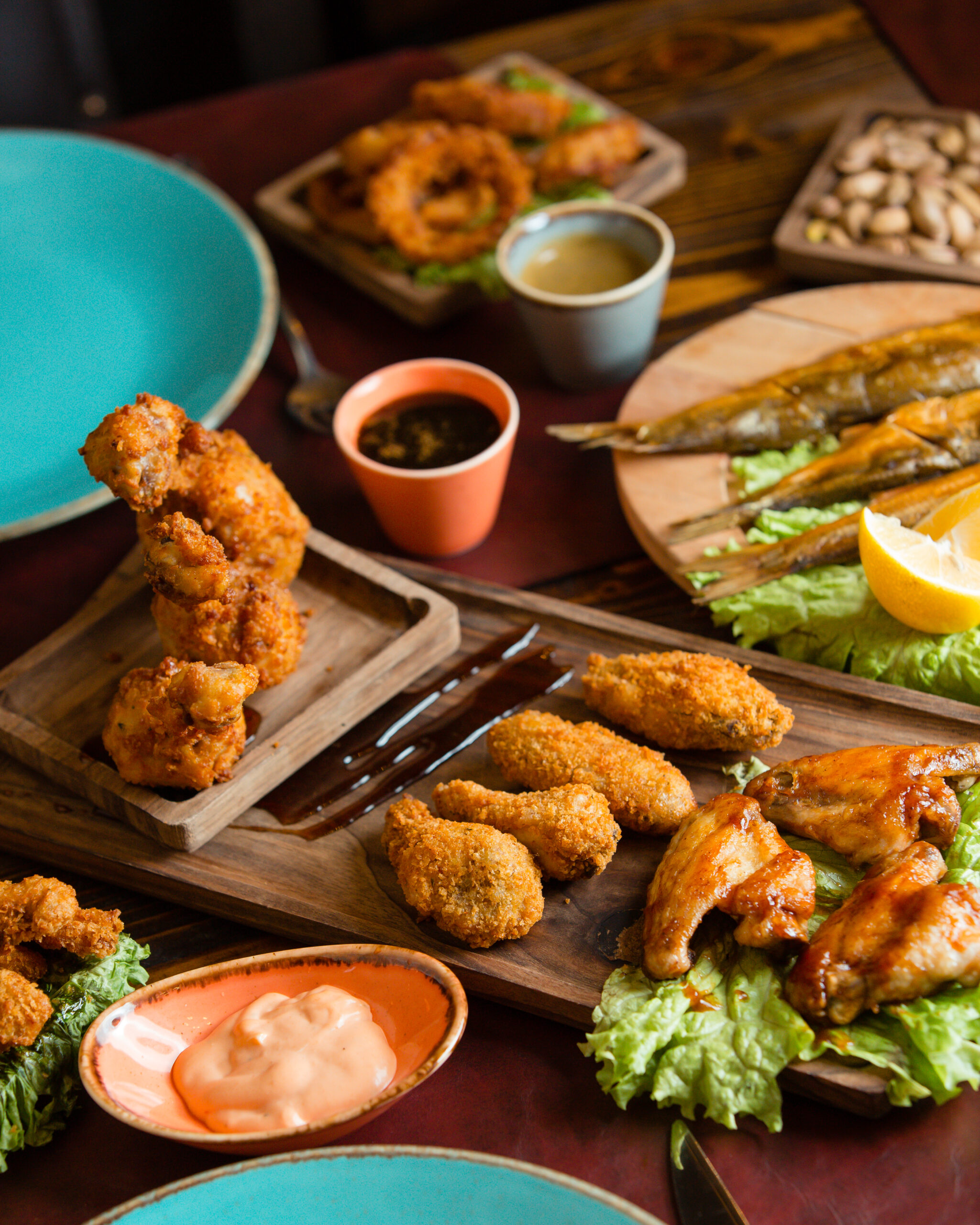 crispy-chicken-nuggets-barbecue-with-sauces-herbs-wooden-platter-with-blue-plates-around