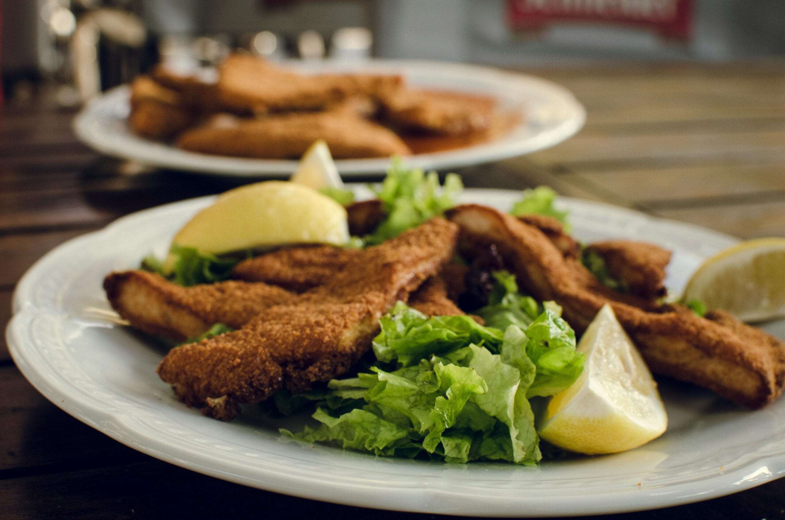 Mouth-watering fried chicken served with lemon wedges and fresh lettuce on a white plate.