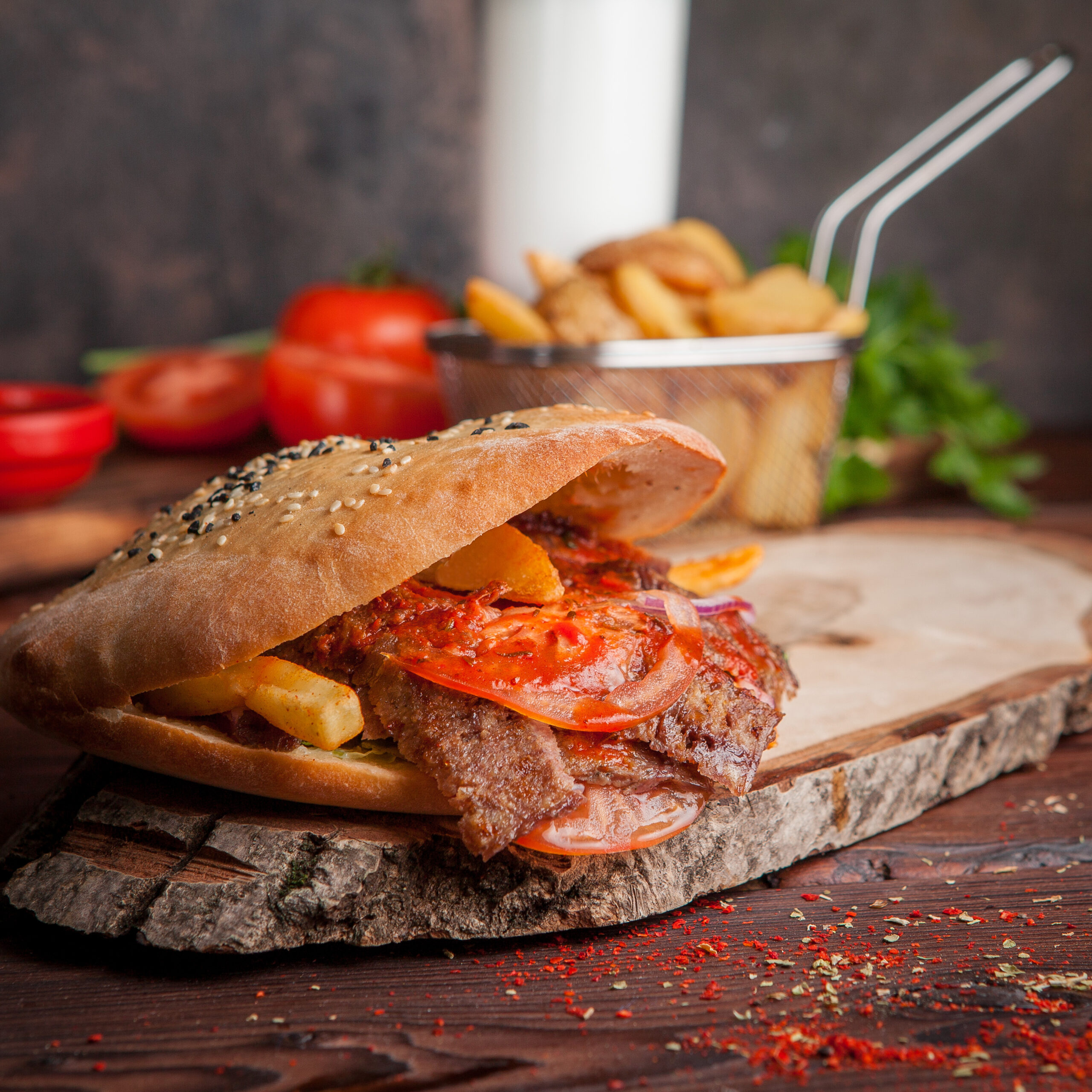 Side view doner with tomato and fried potatoes and bread in board cookware on wooden background